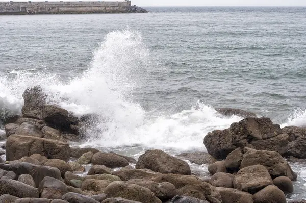 Onde che si infrangono contro rocce — Foto Stock