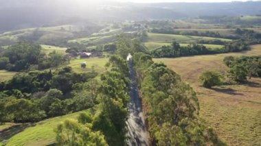 Kırsal kesimde çiftçilik yaparken gün batımı. Dağlar arasında yeşil orman ağaçları.