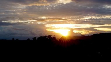Kırsal kesimde çiftçilik yaparken gün batımı. Dağlar arasında yeşil orman ağaçları.