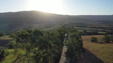 Kırsal kesimde çiftçilik yaparken gün batımı. Dağlar arasında yeşil orman ağaçları.