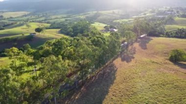 Kırsal kesimde çiftçilik yaparken gün batımı. Dağlar arasında yeşil orman ağaçları.