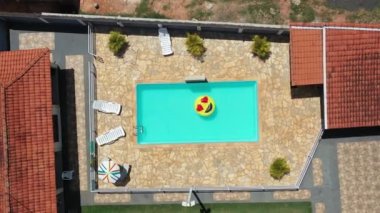 Yüzme havuzunda uçan gülümseme emojisi görüntüsü. Yüzme havuzunda gülen emoji simgesi şamandırası. Yukarıdan aşağıya gülümseme emojisi kırsalda süzülüyor.