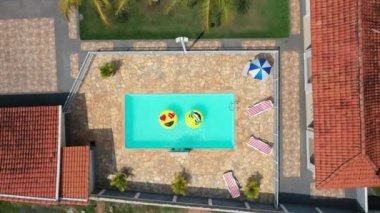 Yüzme havuzunda uçan gülümseme emojisi görüntüsü. Yüzme havuzunda gülen emoji simgesi şamandırası. Yukarıdan aşağıya gülümseme emojisi kırsalda süzülüyor.