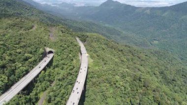 Yeşil orman ağaçları ve dağlarda geniş bir çevre yolu var. Brezilya 'nın güney kıyısına giden ünlü yolda trafik vardı. Çarpıcı mühendislik inşaatı. Ulusal yol simgesi.