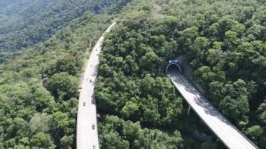 Yeşil orman ağaçları ve dağlardaki Imigrantes karayolu manzaralı. Brezilya 'nın güney kıyısına giden ünlü yolda trafik vardı. Efsanevi mühendislik yapısı. Açık hava yol simgesi..