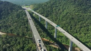 Yeşil orman ağaçları ve dağlardaki Imigrantes karayolu manzaralı. Brezilya 'nın güney kıyısına giden ünlü yolda trafik vardı. Efsanevi mühendislik yapısı. Açık hava yol simgesi..