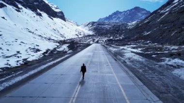 Andes Dağları 'ndaki yolda bir kadın. Santiago Şili yakınlarındaki Los Caracoles otoyolu. Kar manzarası. Kar otoyolu. Yürüyen kadın yolu. Boş yollar. And Dağları 'ndaki yollarda bir kadın.