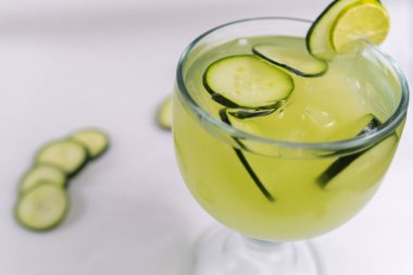 Beyaz yüzeyde salatalık ve limon ferahlatıcı içecek.