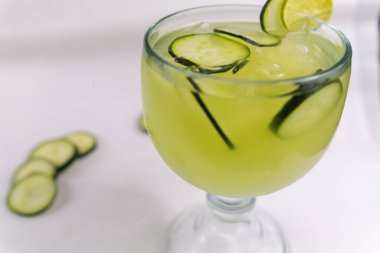 Beyaz yüzeyde salatalık ve limon ferahlatıcı içecek.