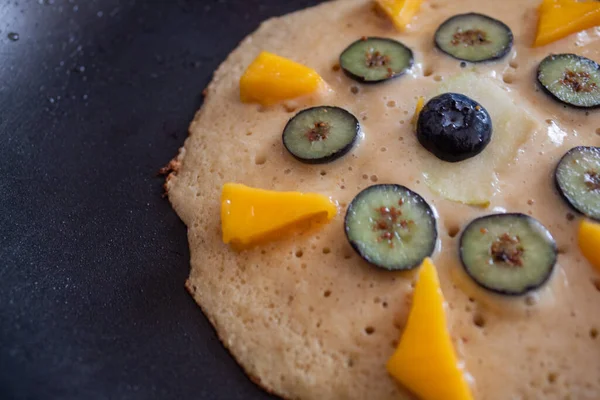 Panqueque crudo con rodajas de fruta en una sartén — Foto de Stock