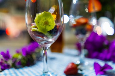 Çilek ve kivi dilimleri şarap kadehinde bulanık arkaplanlı.