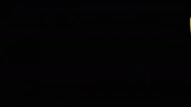 Siyah arkaplanlı cam kadehte köpüklü bir bira tutuyor.