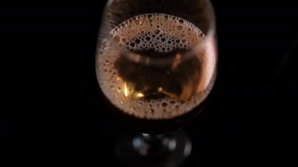 Bubbly beer in a glass goblet with black background — Stock Video