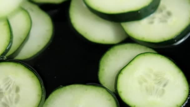 Close-up of group of fresh cucumber slices floating in liquid — Stock Video