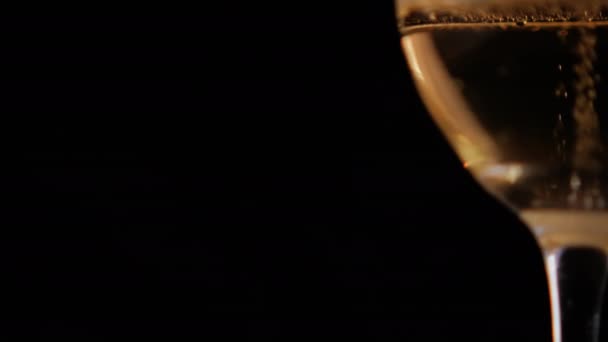 Siyah arka planlı cam bir kadehte köpüklü biranın yakın çekimi. — Stok video