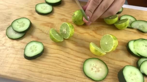 Händer skivning lime på en trä skärbräda med gurka skivor — Stockvideo