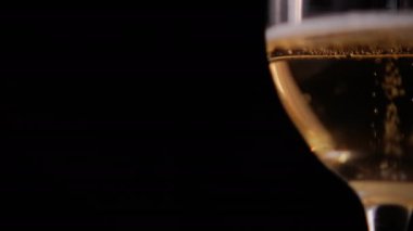 Siyah arkaplanlı cam kadehteki köpüklü biranın yakın çekimi.