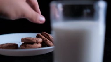 Bir bardak sütün arkasındaki tabaktan kurabiye kapmak.