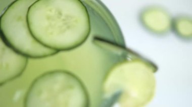 Beyaz yüzeyde salatalık ve limon ferahlatıcı içecek.