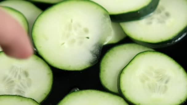 Close-up van een groep verse komkommerschijfjes die in vloeibare vorm drijven — Stockvideo
