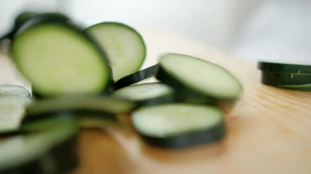 Rodajas de pepino cayendo sobre tabla de cortar de madera en cámara lenta — Vídeo de stock