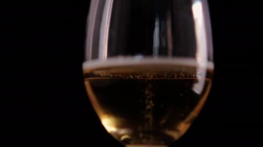 Siyah arkaplanlı cam kadehteki köpüklü biranın yakın çekimi.