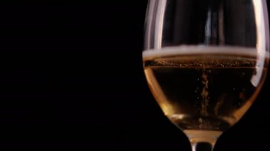 Siyah arka planlı cam bir kadehte köpüklü bira