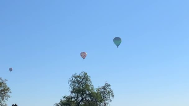Üç renkli sıcak hava balonu açık mavi gökyüzünde uçuyor. — Stok video