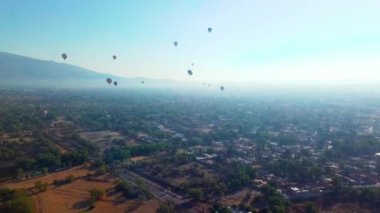 Sıcak hava balonlarının ağaçların ve evlerin üzerinde uçuşması hayret verici bir manzara.