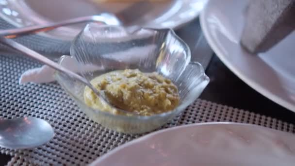 Gul pudding eller dressing i liten glasskål omgiven av plattor — Stockvideo