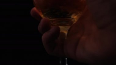 Siyah arkaplanlı cam kadehte köpüklü bir bira tutuyor.