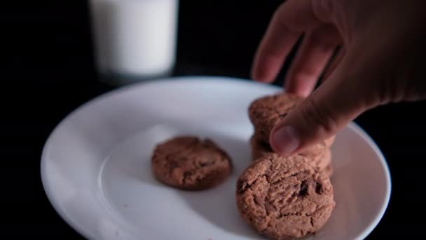 牛乳のガラスの横にプレート上にクッキーを積み重ねる手 — ストック動画