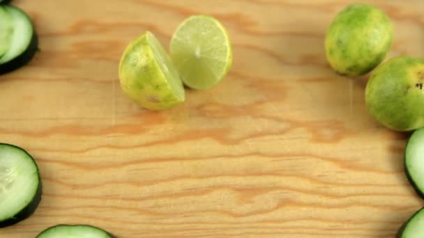 Felezett lime és friss uborkaszelet fából készült vágódeszkán — Stock videók