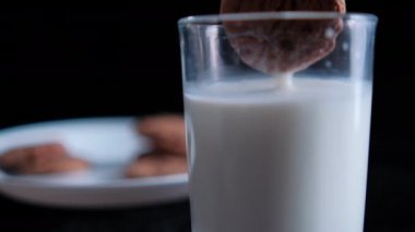 Siyah arka planı olan bir kurabiye bardağına daldırmak.