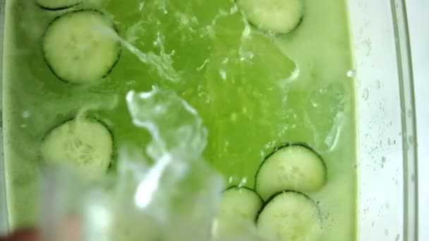 Aruncarea cuburilor de gheață într-o băutură răcoritoare de castraveți în recipient de sticlă — Videoclip de stoc