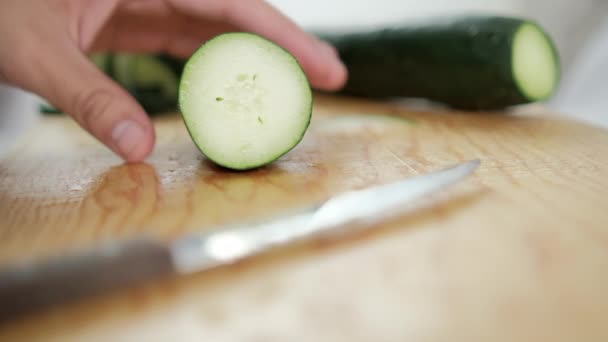Hands slicing fresh cucumber on a wooden cutting board — Stock Video