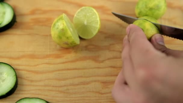 Händer skivning lime på en trä skärbräda med gurka skivor — Stockvideo