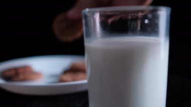 Siyah arka planı olan bir kurabiye bardağına daldırmak.