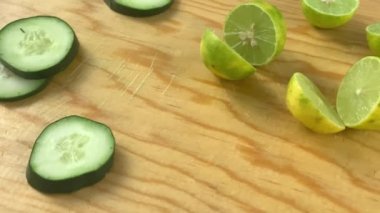 Yarım limon ve ahşap kesme tahtasındaki taze salatalık dilimleri.