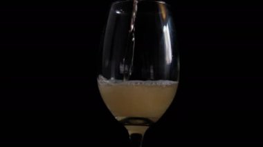 Siyah arkaplanlı cam bir kadehe bira dökmek.