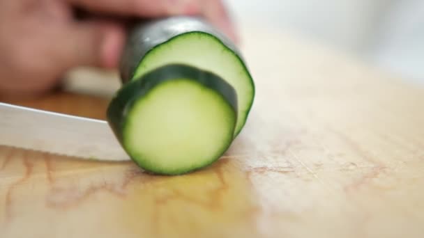 Händer skivning färsk gurka på en trä skärbräda — Stockvideo