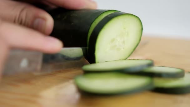 A kezek friss uborkát szeletelnek egy fa vágódeszkán. — Stock videók
