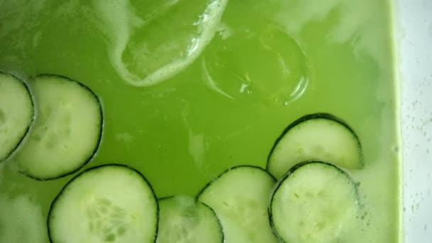 Osvěžující okurkový nápoj ve skleněné nádobě nad bílým povrchem — Stock video