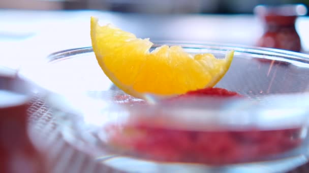 Rebanada de naranja y polvo de chile en la placa de vidrio encima de la alfombra de mesa gris — Vídeos de Stock