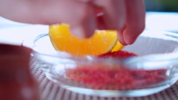 Tangan menutupi irisan oranye dengan bubuk cabai di piring kaca — Stok Video