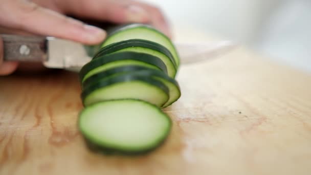 Handen snijden verse komkommer op een houten snijplank — Stockvideo