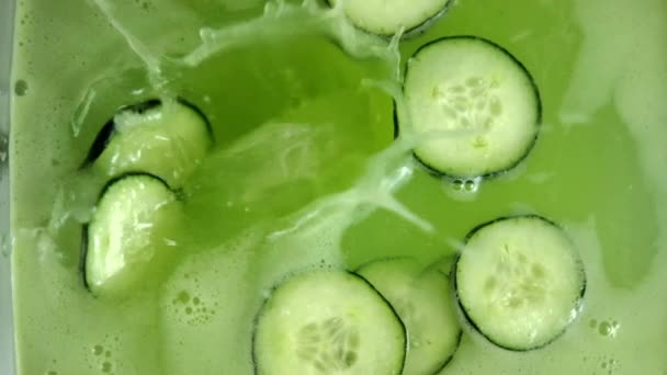 Goccia grande pezzo di ghiaccio in bevanda rinfrescante cetriolo in contenitore di vetro — Video Stock