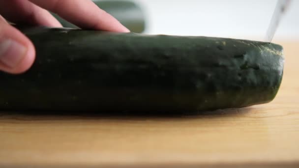 Händer skivning färsk gurka på en trä skärbräda — Stockvideo