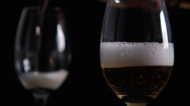 Siyah arkaplanlı cam kadehlere bira dökülüyor. — Stok video