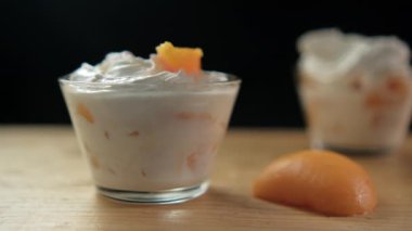 Ahşap yüzeyde siyah yüzeyi olan şeftali ve krema kapları.